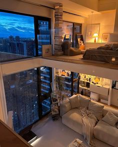 a living room filled with furniture and a large window overlooking the city at night time