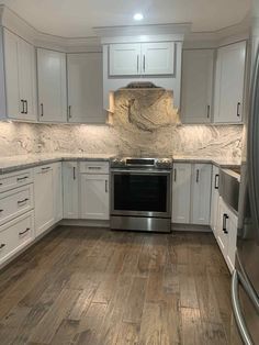 an empty kitchen with white cabinets and wood flooring is pictured in this image from the front view