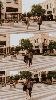 two people walking across a cross walk in front of some buildings and trees, one holding the other's hand