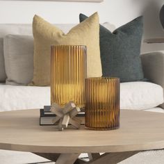 two glass vases sitting on top of a wooden table next to a white couch