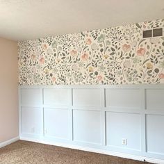 an empty room with white paneling and floral wallpaper on the walls in it