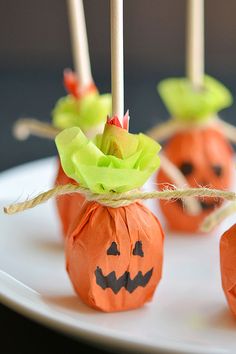 candy apples decorated like pumpkins on a white plate