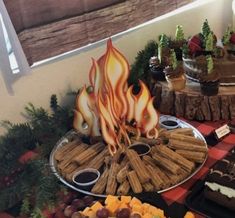 an assortment of desserts and snacks displayed on a buffet table with fire theme decorations