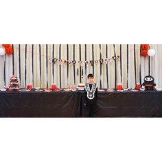 a young boy standing in front of a table with cake on it and decorations around him