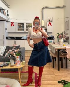 a woman is taking a selfie in her living room wearing red boots and a white crop top