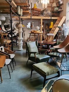 a room filled with lots of different types of chairs and tables in front of a window