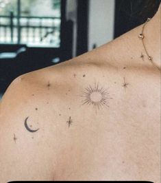 the back of a woman's shoulder with stars and moon tattoos on her chest