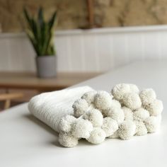 a pile of white towels sitting on top of a table next to a potted plant