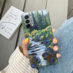 a woman holding up her phone case with a painting on it