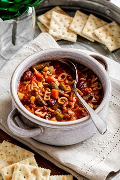 a bowl of pasta soup with crackers on the side