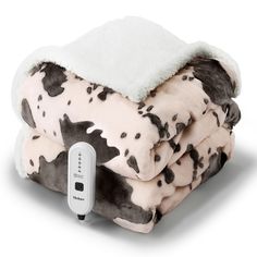 a blanket that is sitting on top of a white and black blanket with a cell phone plugged into it