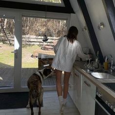 a woman standing in a kitchen next to a dog