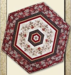 a red and white quilted table topper with an intricate design on it's center