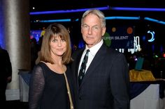 a man and woman standing next to each other in front of a table with blue lights