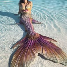 a woman is laying in the water with a mermaid tail