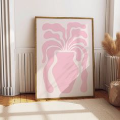 a pink and white art print on a wall next to a vase with dry grass in it