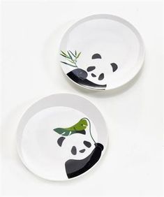 two plates with pandas painted on them are sitting next to each other, one has a bamboo plant in its mouth