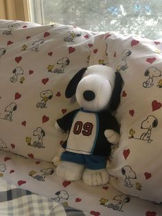 a stuffed dog sitting on top of a bed next to pillows and sheets with hearts