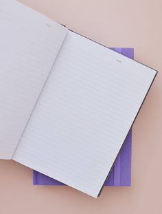 an open notebook sitting on top of a purple pad next to a pink and white wall