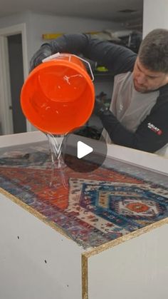 a man is pouring water into an orange bowl