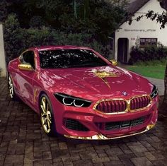 a red sports car parked in front of a white house with gold lettering on it