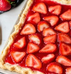 a pie with strawberries on top is sitting on a table