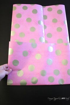 a hand is holding two pieces of pink and green polka dot paper