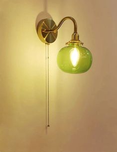 a green light hanging from the side of a wall next to a lamp on a white wall