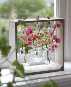 three vases with flowers in them sitting on a window sill