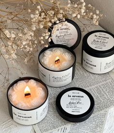 three candles sitting next to each other on top of a newspaper with flowers in the background