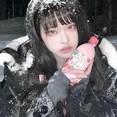 a woman holding a bottle in the snow with her hand on her shoulder and looking at the camera