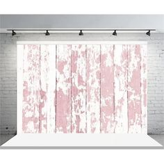 a white brick wall with pink paint on it and some lights hanging from the ceiling