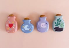 four ceramic vases with plants and animals painted on the sides, lined up against a pink background