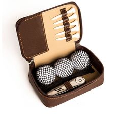 three golf balls in a brown case on a white surface with two forks and a knife