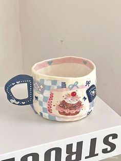 a ceramic cup sitting on top of a white shelf next to a sign with the word donuts printed on it