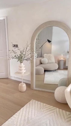 a living room with white furniture and a large mirror