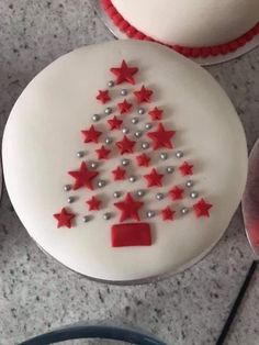 a white cake decorated with red stars and a small christmas tree on the top, surrounded by other cupcakes