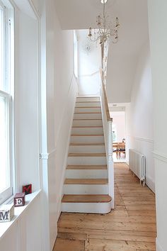 a staircase leading up to the first floor in a house with white walls and wood floors