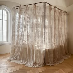 an open curtain in front of a window with wooden floors and white curtains on it