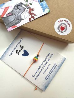 an open box with a card and a bracelet on it