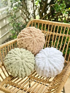 three pillows sitting on top of a wicker chair