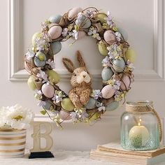 a wreath with an easter bunny sitting on top of it next to candles and flowers