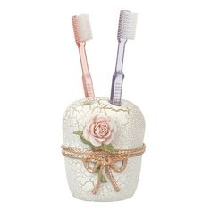 two toothbrushes sitting in a decorative container with lace and pink flowers on it