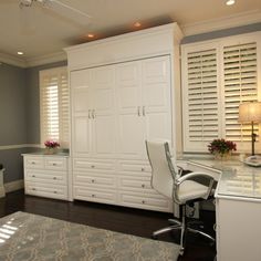 a white desk and chair in a room with shutters on the window sill