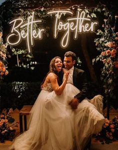 a bride and groom sitting on a bench under a neon sign that says better together