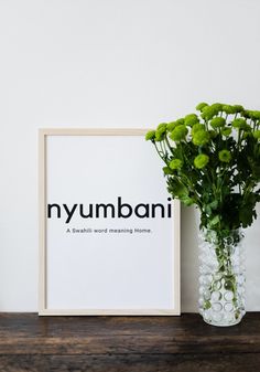 a vase filled with green flowers next to a framed print that says nyymbani