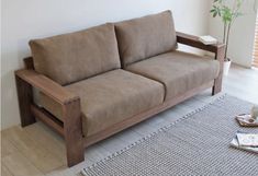 a brown couch sitting on top of a wooden floor next to a white rug and window