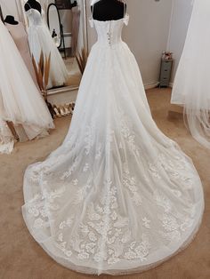 a white wedding dress on display in a bridal room with mannequins