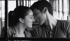 a man and woman sitting next to each other in front of a metal fence with their eyes closed