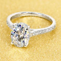 a diamond ring on a gold background with sparkles around the band and center stone